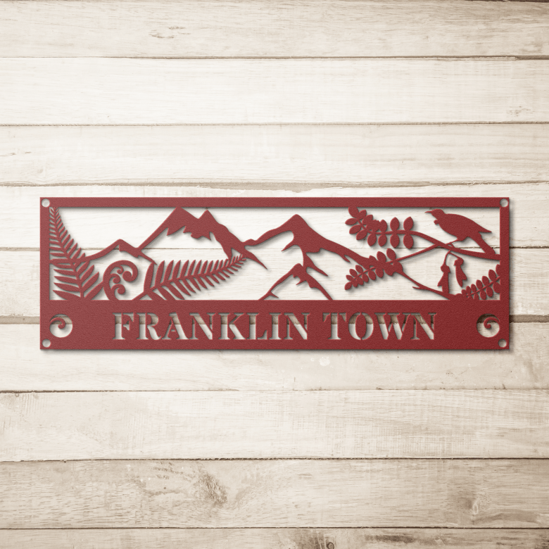 New Zealand scenery-themed red wall art on a simple wood background, highlighting the ponga fern and sacred maunga