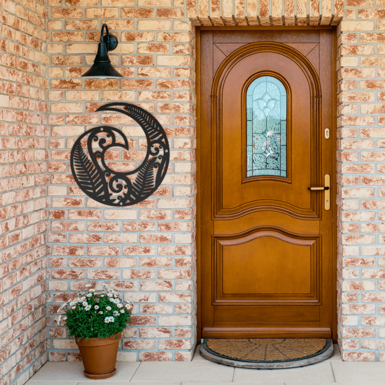 Black powder-coated Koru metal wall art at brick entryway exterior