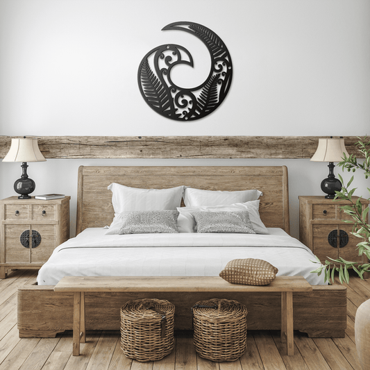 Black Koru metal wall art hanging on a light-colored wall above a wooden bench with green plants, creating spiritual space.