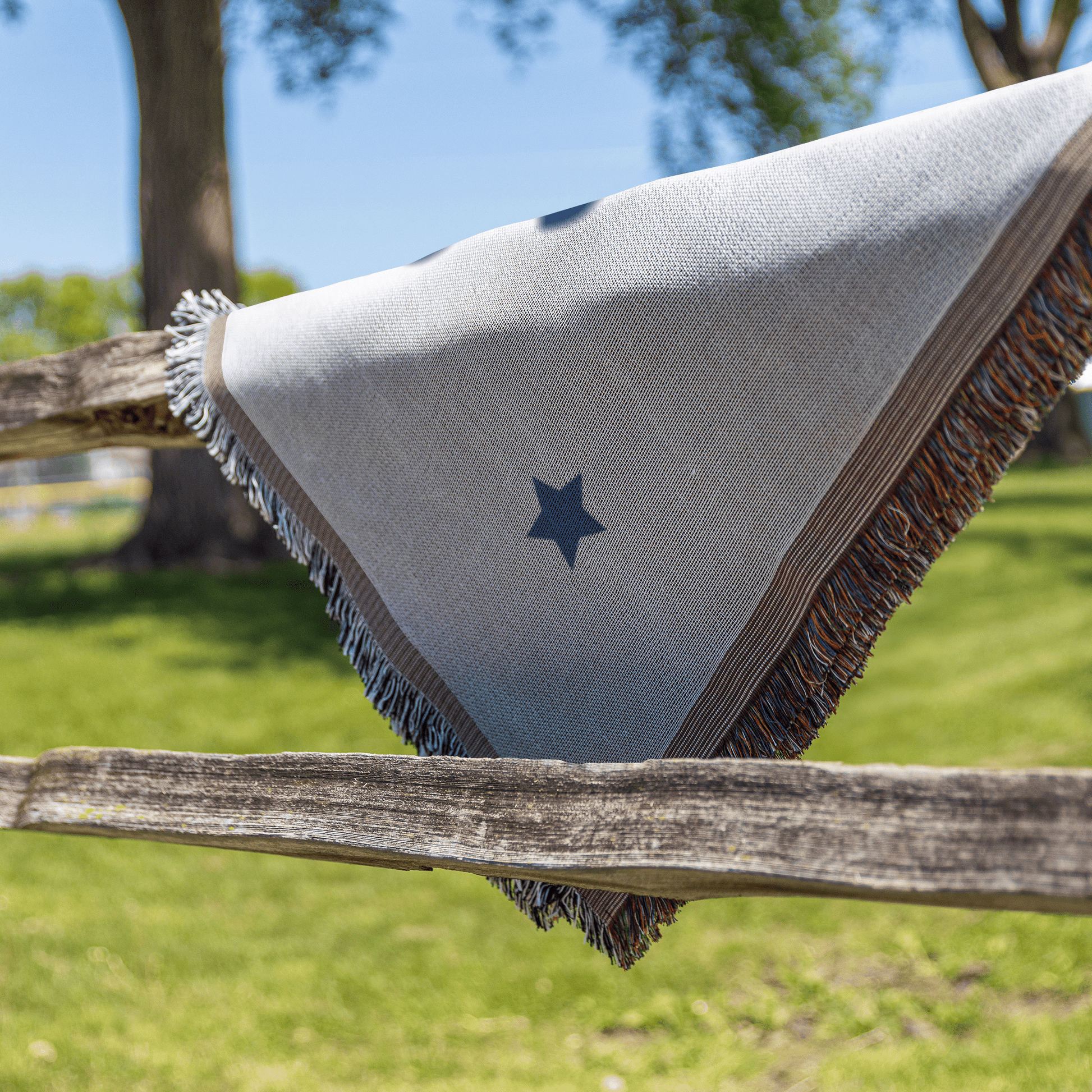 Textile with a star design draped over a wooden fence outdoors