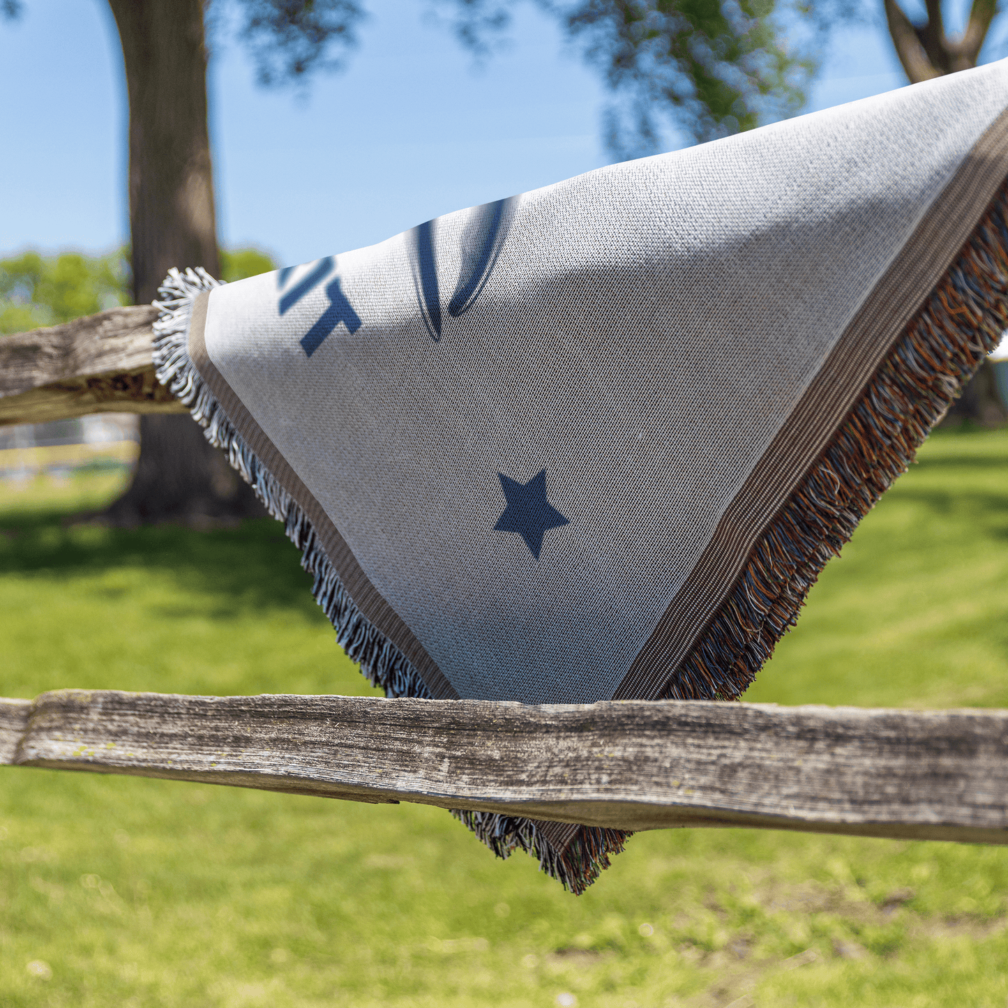 Textile with star design draped over a wooden fence in an outdoor setting