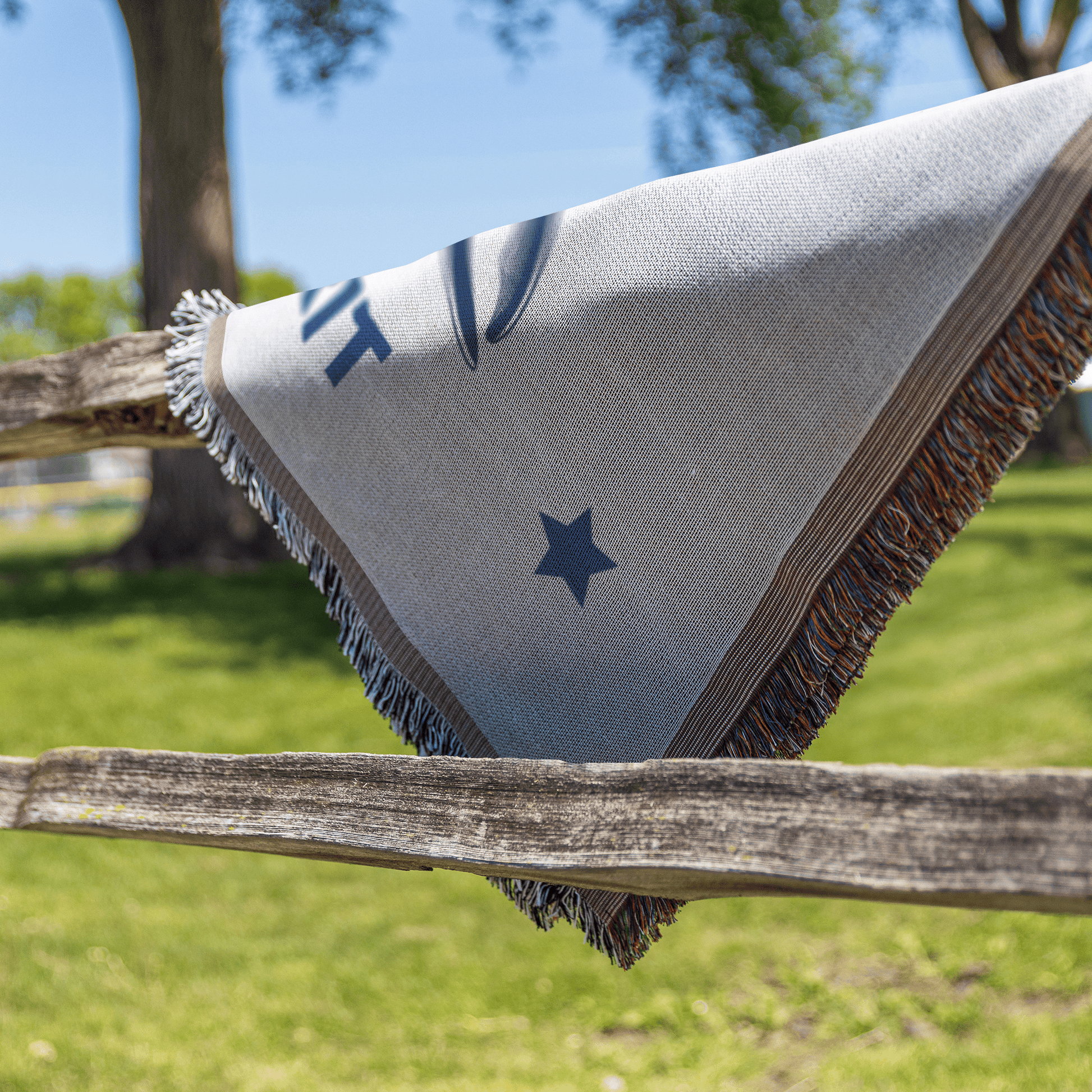 Textile with star design draped over a wooden fence in an outdoor setting