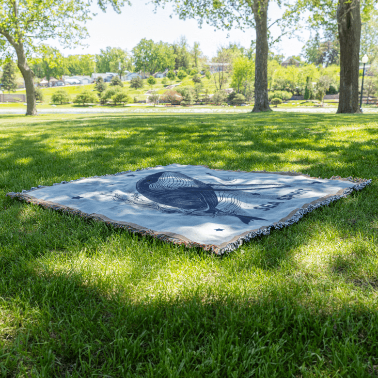 Sea Spirit woven blanket laid on grass, perfect for outdoor picnics and meditation