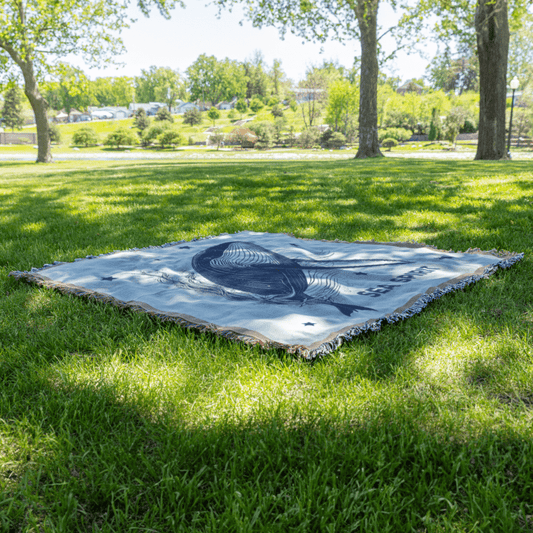 Sea Spirit woven blanket laid on grass, perfect for outdoor picnics and meditation